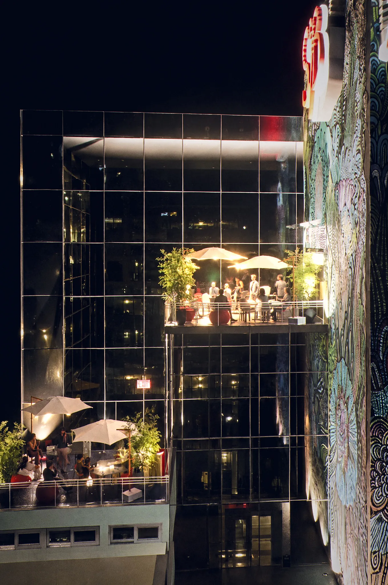 Stacked terraces at night beside a mural